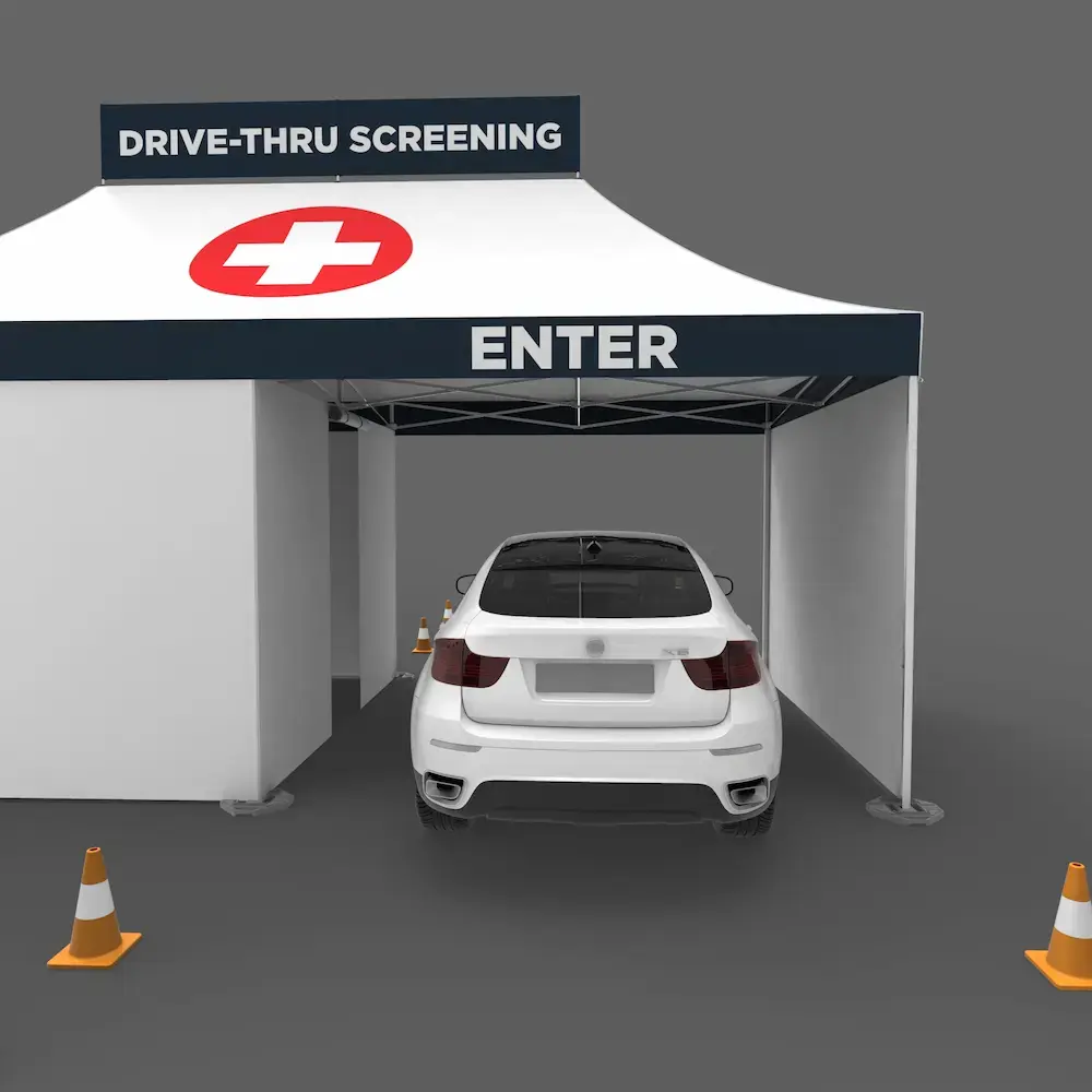 the drive-in entrance of a white drive thru coronavirus testing tent with custom printing