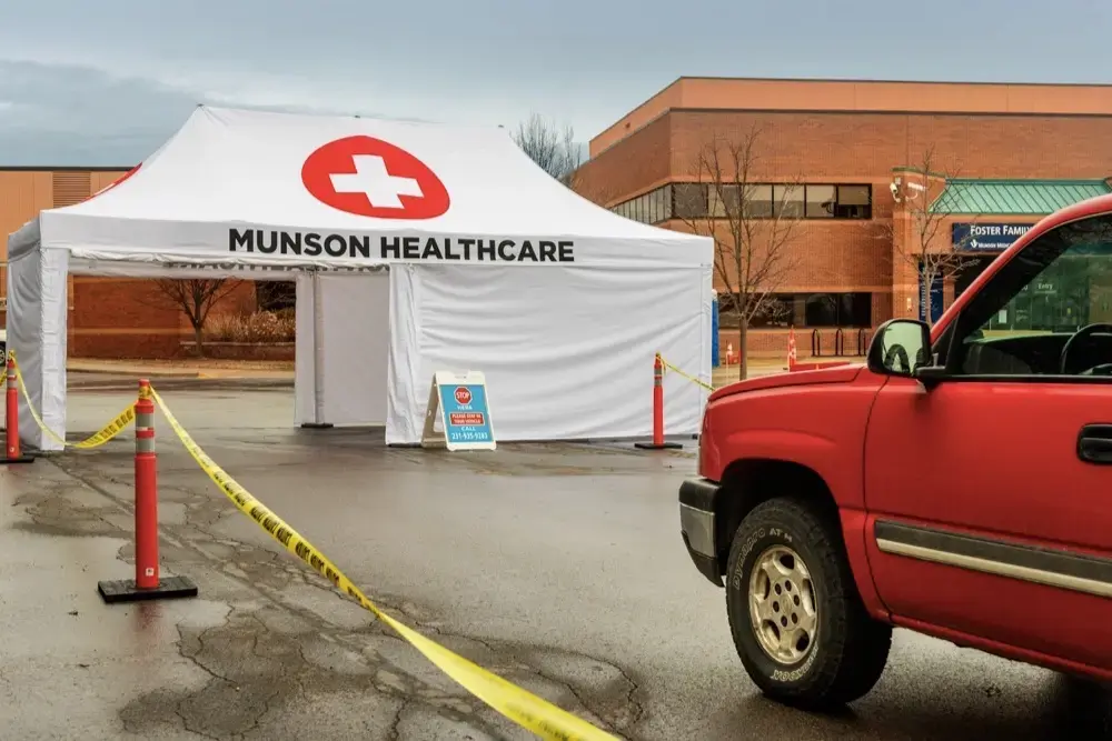 a truck pulling into a custom printed covid-19 drive thru screening tent for Munson Medical Center