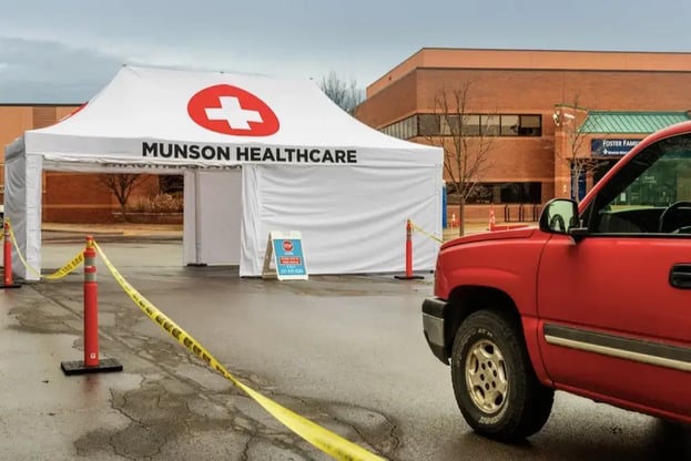 a truck pulling into a custom printed covid-19 drive thru screening tent for Munson Medical Center
