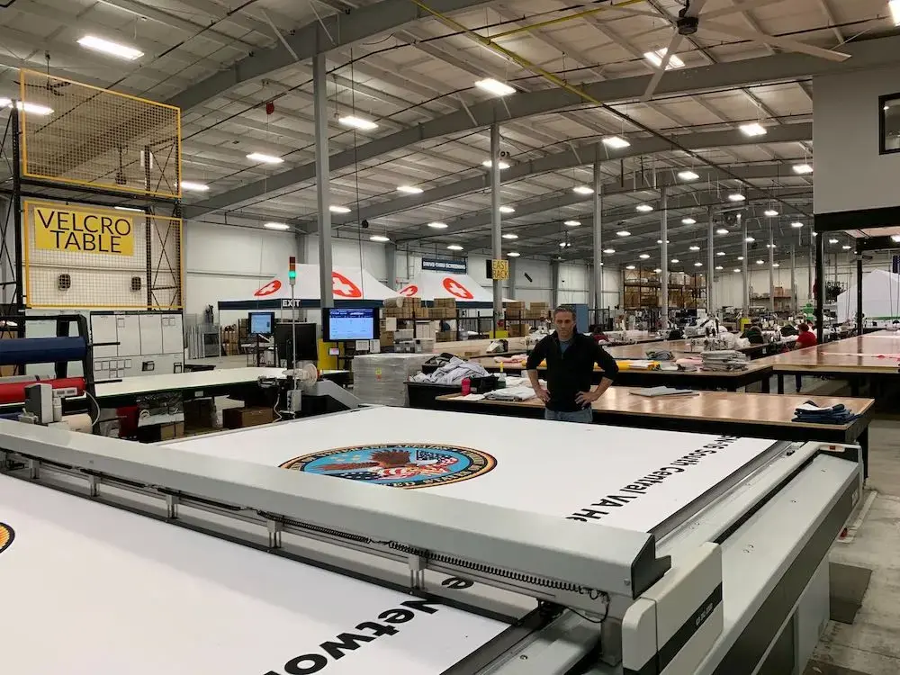 a zund machine printing the VA logo on white material at TentCraft’s US manufacturing facility